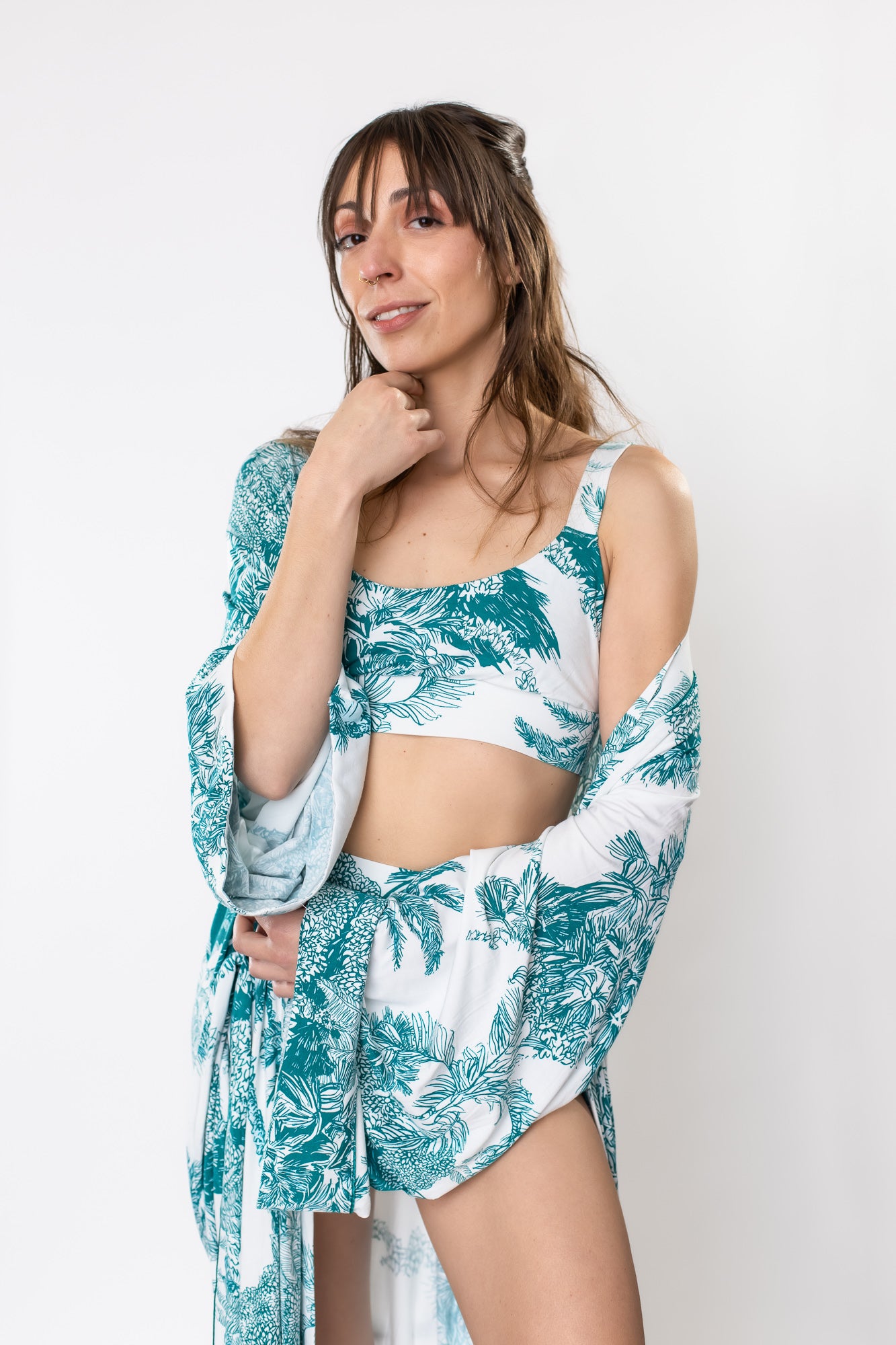 Woman posing in a bamboo bralette, brief, and robe with a teal palm leaf pattern