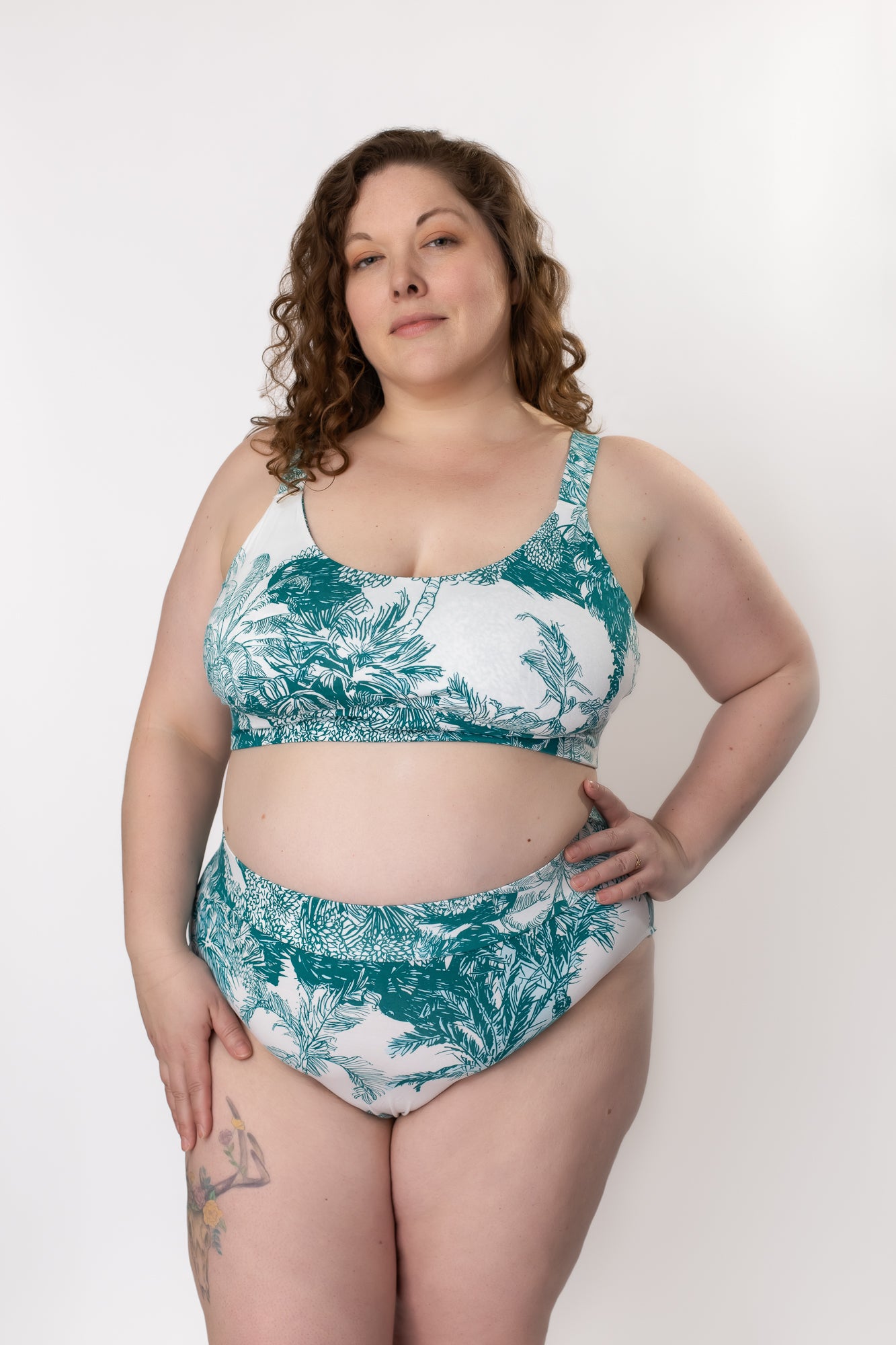 Woman standing in a bra and panty set made of bamboo fabric with a teal palm leaf print