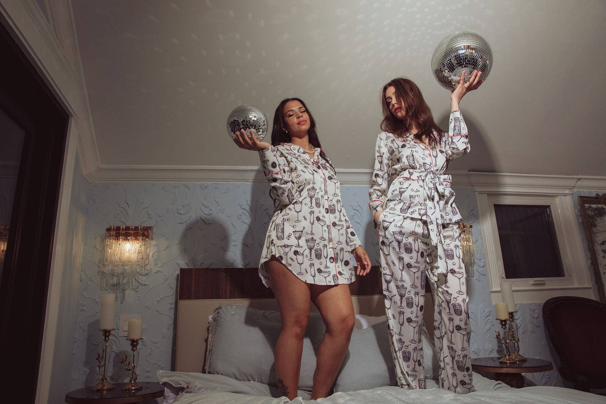 Women standing on a bed in pajamas holding disco balls