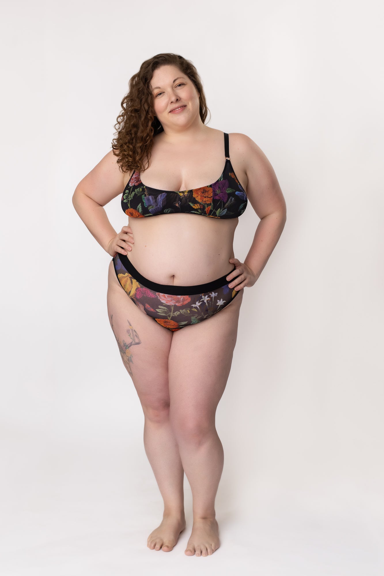 Plus-size woman standing in a black floral mesh bra and panty set