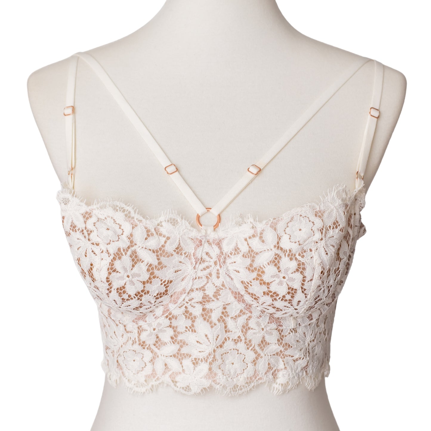 Front of a white lace bustier with rose gold hardware and straps across the bust