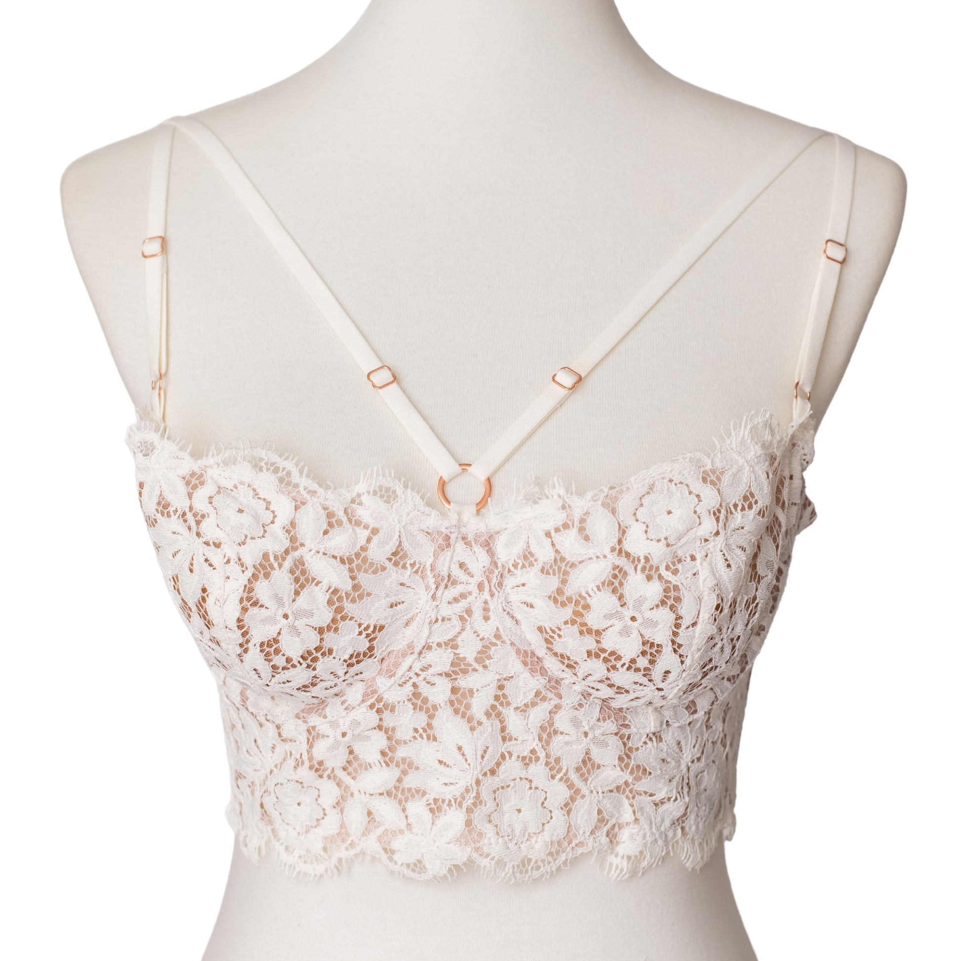 Front of a white lace bustier with rose gold hardware and straps across the bust