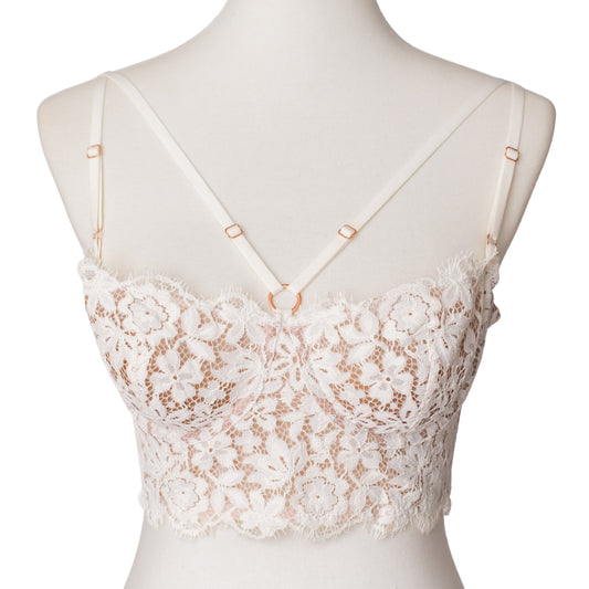 Front of a white lace bustier with rose gold hardware and straps across the bust