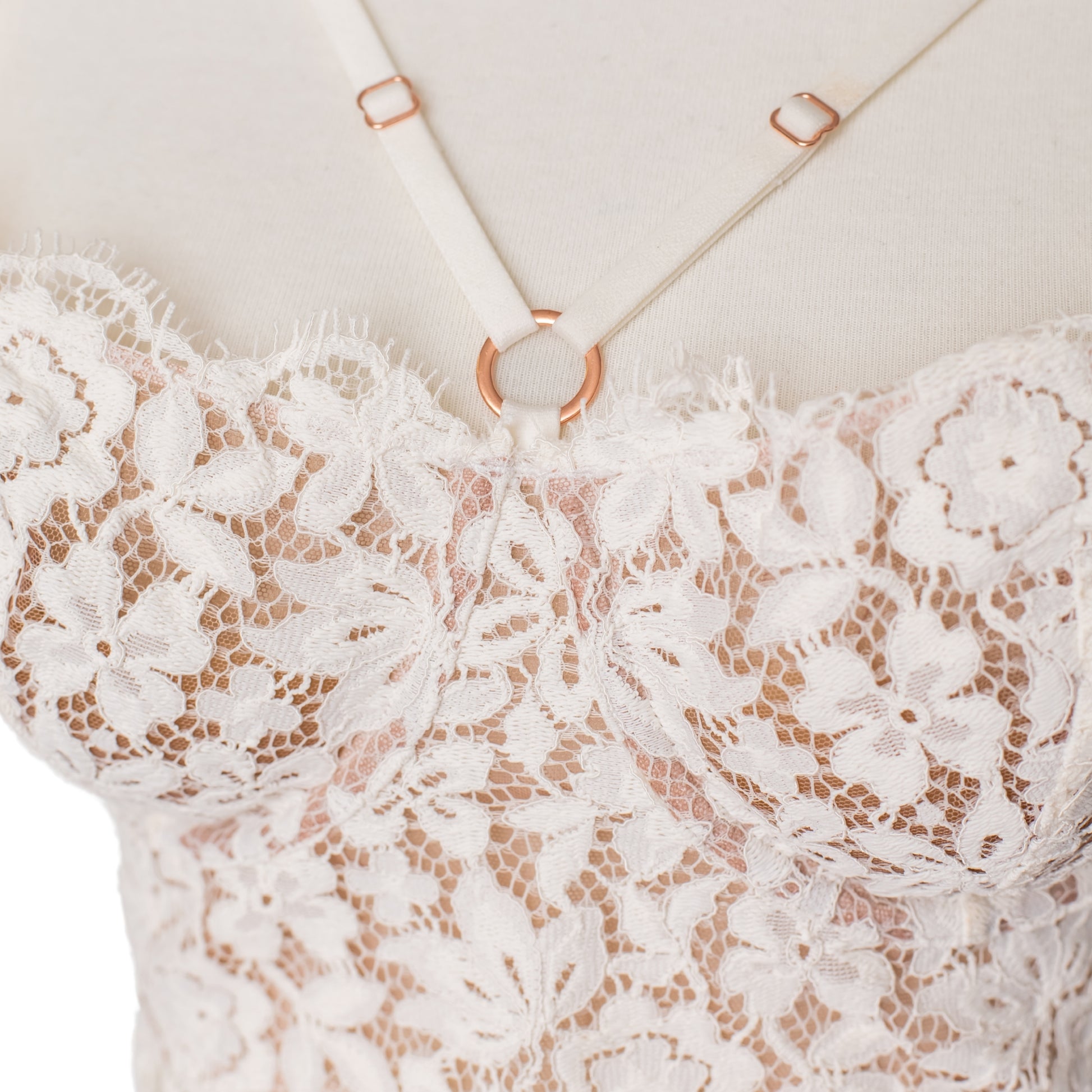 Close up of white lace and rose gold hardware on a bustier