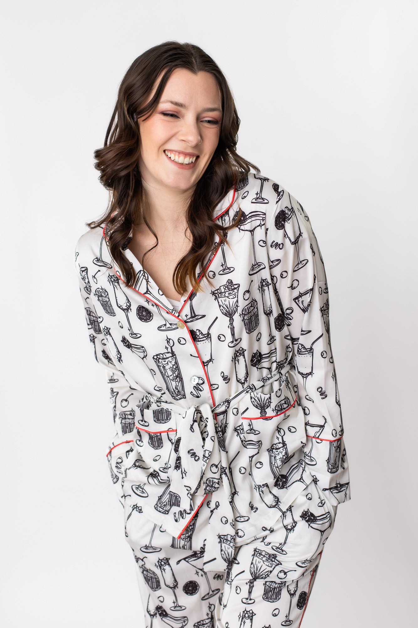White woman smiling in a cocktail print satin pajama set