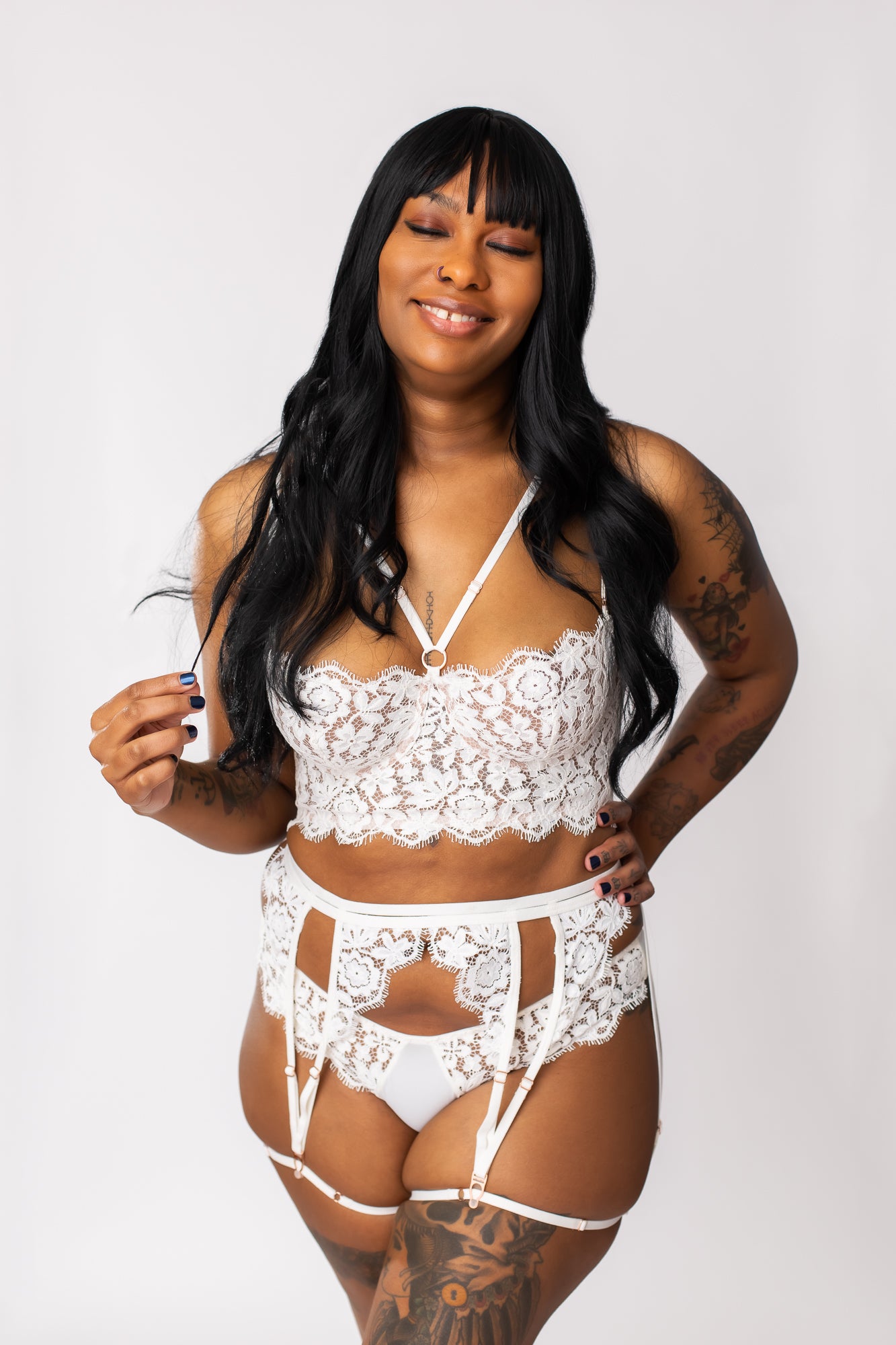 Front view of a woman wearing a white lace lingerie set with a bustier, panty, garter belt, and leg garters